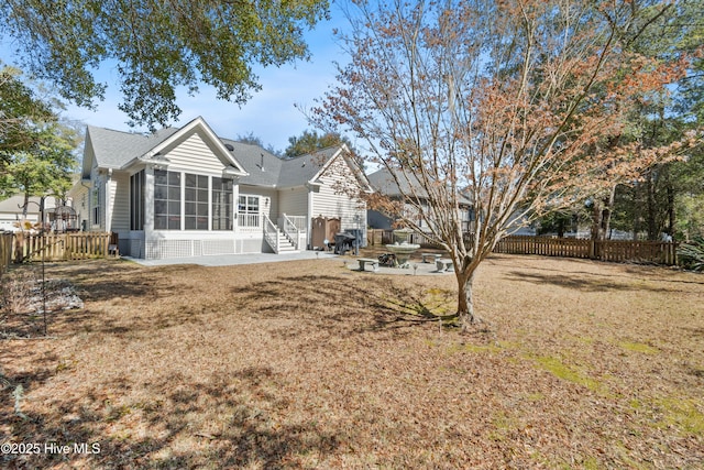 rear view of property featuring a yard, a patio, a fenced backyard, and a sunroom