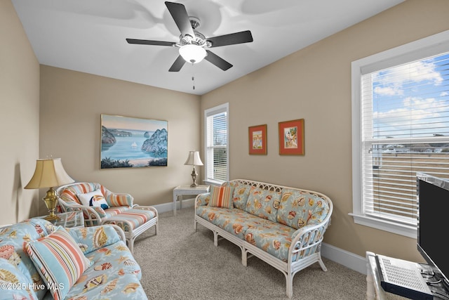 carpeted living area featuring ceiling fan and baseboards