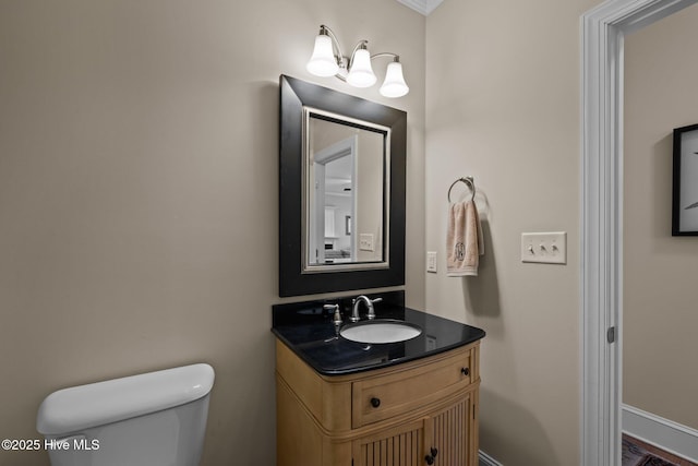 half bath featuring vanity, toilet, and baseboards