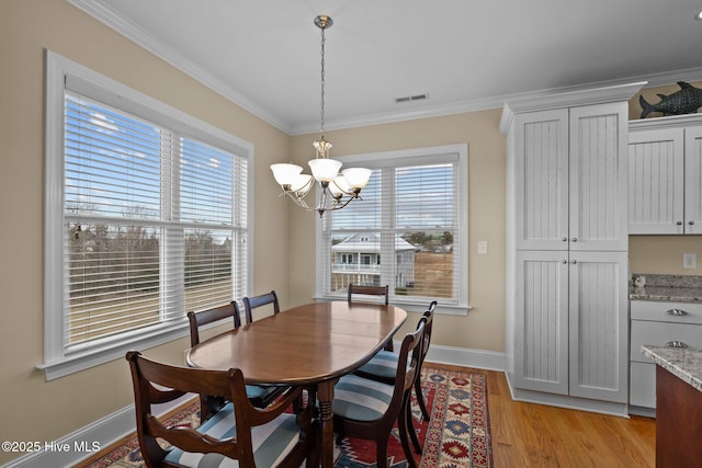 dining space with light wood-type flooring, baseboards, an inviting chandelier, and ornamental molding