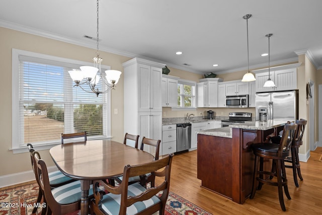 dining area with visible vents, light wood-type flooring, crown molding, and baseboards