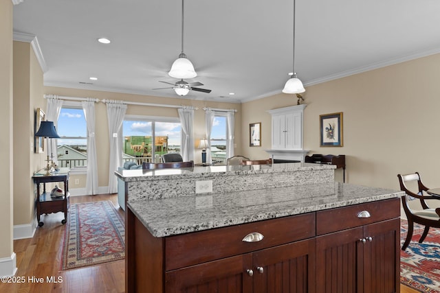 kitchen with crown molding, light wood-style flooring, baseboards, and open floor plan