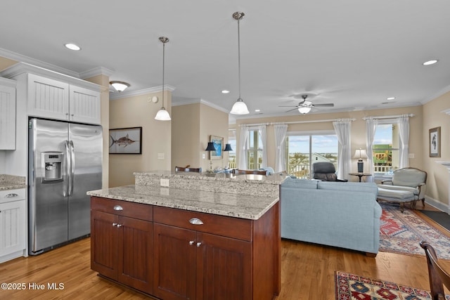 kitchen with light wood-style flooring, stainless steel fridge with ice dispenser, ornamental molding, white cabinetry, and decorative light fixtures