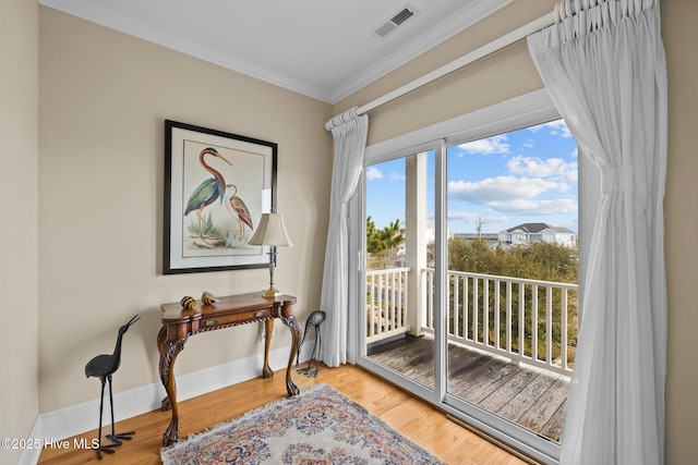 interior space featuring visible vents, baseboards, wood finished floors, and crown molding