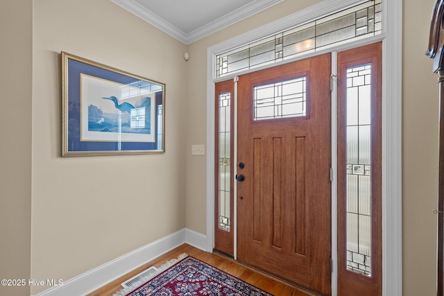 entrance foyer featuring visible vents, crown molding, baseboards, and wood finished floors