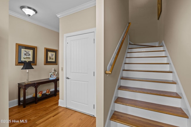 stairway featuring crown molding, wood finished floors, and baseboards