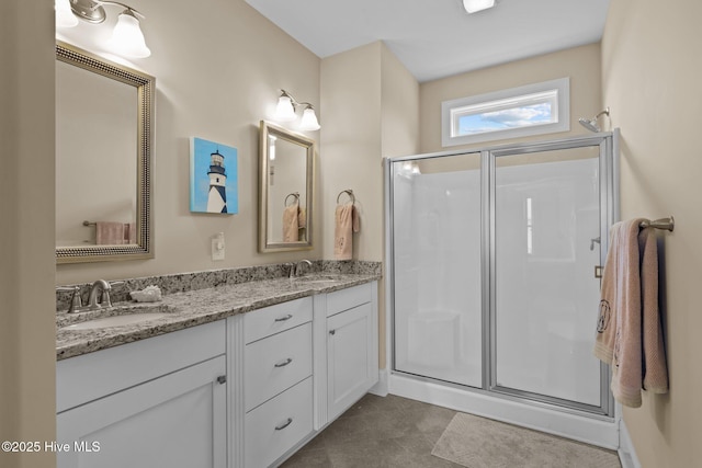 bathroom featuring a sink, a stall shower, and double vanity