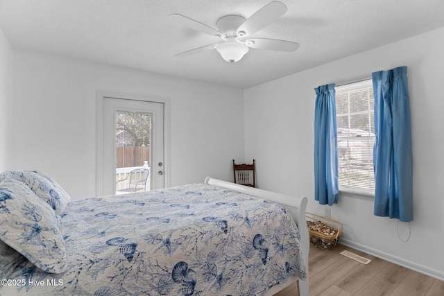 109 NE 17th St, Oak Island, NC 28465 - bedroom featuring wood finished floors, access to exterior, baseboards, and a ceiling fan