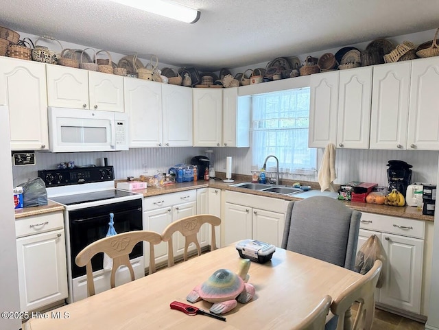 kitchen with white microwave, electric range, white cabinetry, and a sink