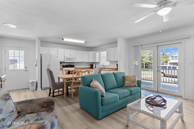 109 NE 17th St, Oak Island, NC 28465 - living room featuring a textured ceiling, plenty of natural light, light wood-style flooring, and a ceiling fan