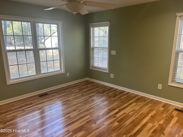 spare room featuring a ceiling fan, wood finished floors, visible vents, and baseboards