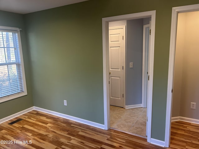 unfurnished room featuring visible vents, baseboards, and wood finished floors