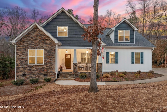 craftsman house featuring stone siding, covered porch, roof with shingles, and crawl space