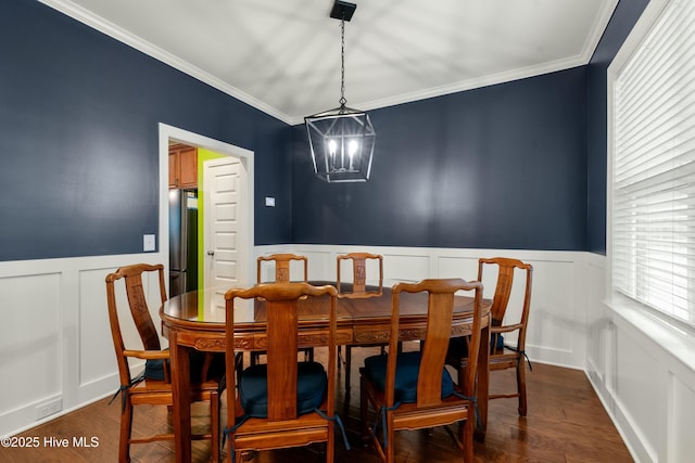 dining room with a notable chandelier, dark wood-type flooring, wainscoting, and crown molding