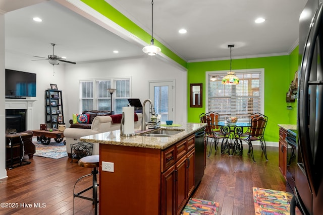 kitchen with black appliances, a breakfast bar area, dark wood-type flooring, and a sink