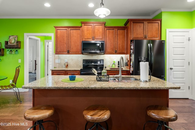 kitchen with decorative backsplash, black appliances, a breakfast bar area, and ornamental molding