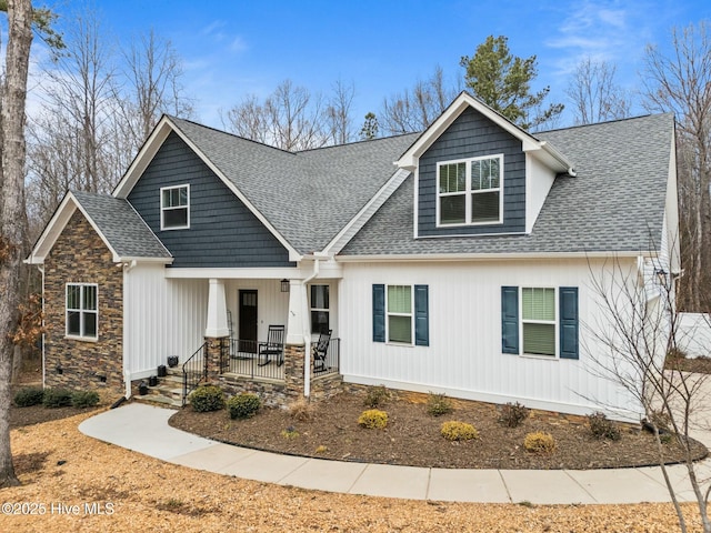 craftsman inspired home with a porch, stone siding, and roof with shingles