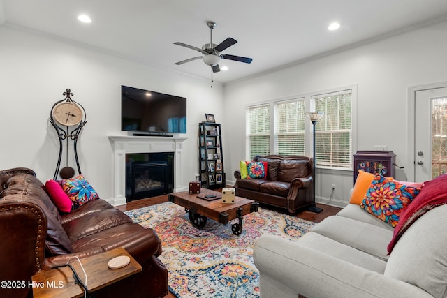 living area with a glass covered fireplace, recessed lighting, ceiling fan, and wood finished floors