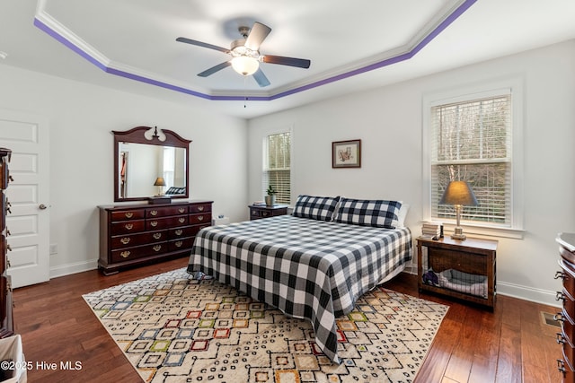 bedroom featuring dark wood finished floors, ceiling fan, a raised ceiling, and baseboards