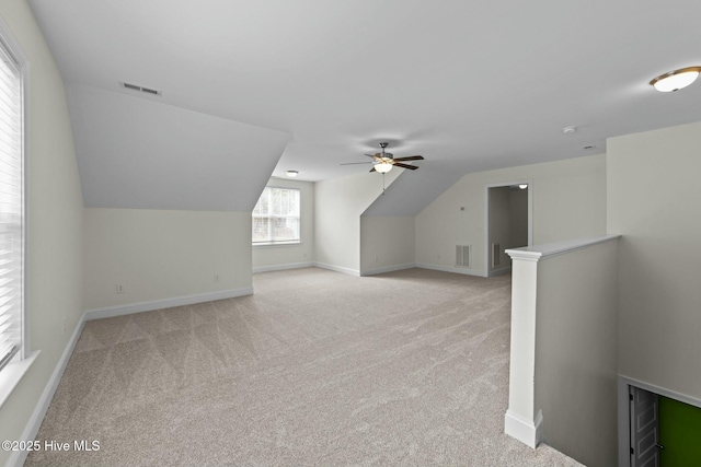 bonus room featuring visible vents, baseboards, light colored carpet, and vaulted ceiling