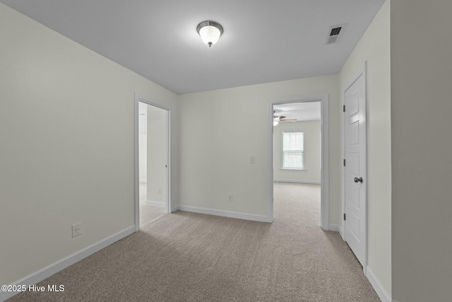 empty room with baseboards, visible vents, and light carpet