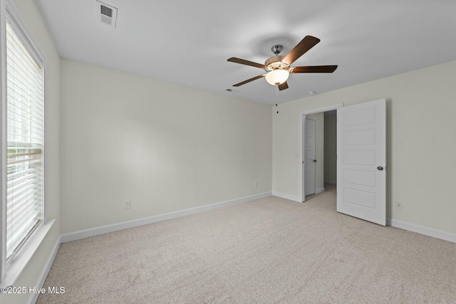 empty room with ceiling fan, visible vents, baseboards, and light carpet