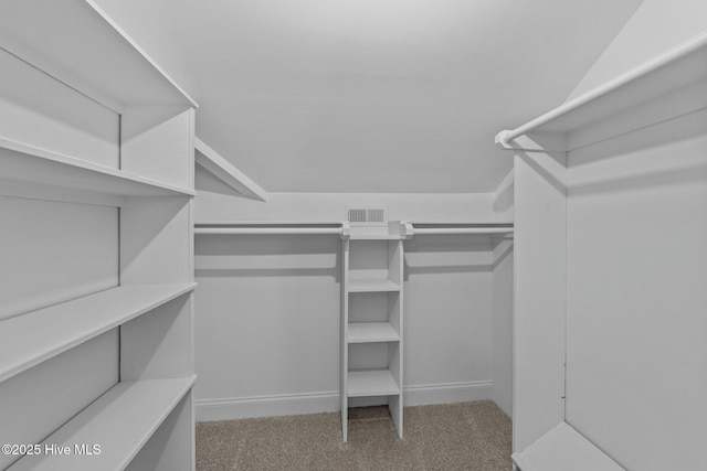 walk in closet featuring vaulted ceiling, visible vents, and carpet floors