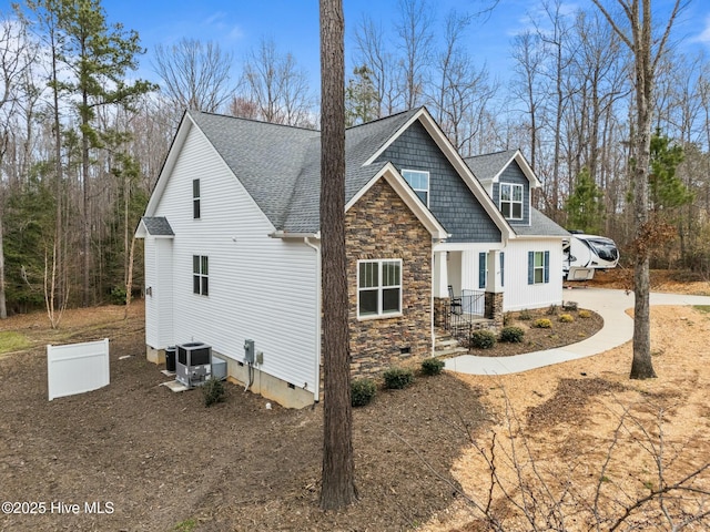 view of property exterior with a shingled roof, central AC unit, stone siding, and crawl space