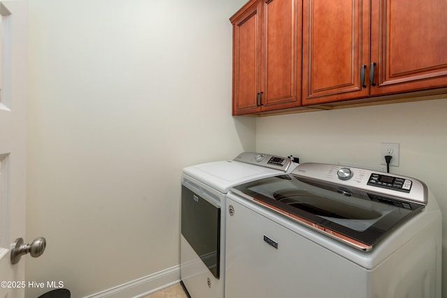 washroom featuring baseboards, cabinet space, and separate washer and dryer