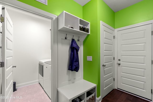 mudroom with dark tile patterned floors, washing machine and dryer, and baseboards