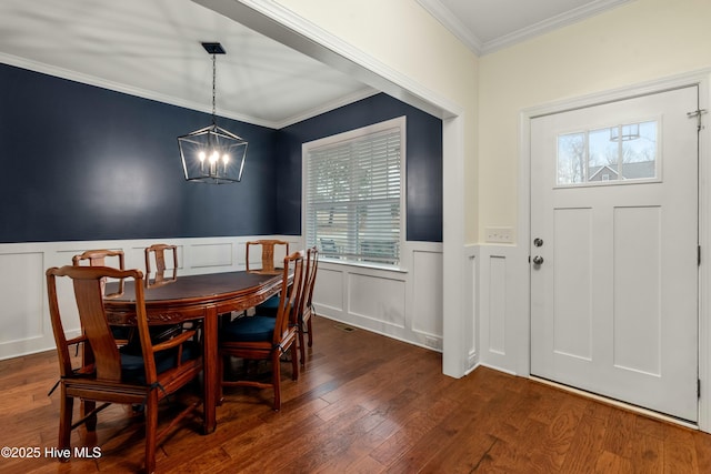 dining room with a healthy amount of sunlight, wood finished floors, an inviting chandelier, and ornamental molding