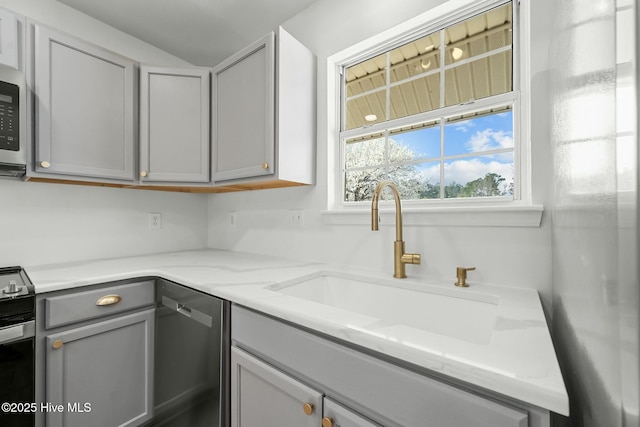 kitchen featuring gray cabinetry, a sink, light stone counters, stainless steel dishwasher, and electric range oven