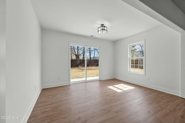 spare room featuring wood finished floors, baseboards, and a wealth of natural light