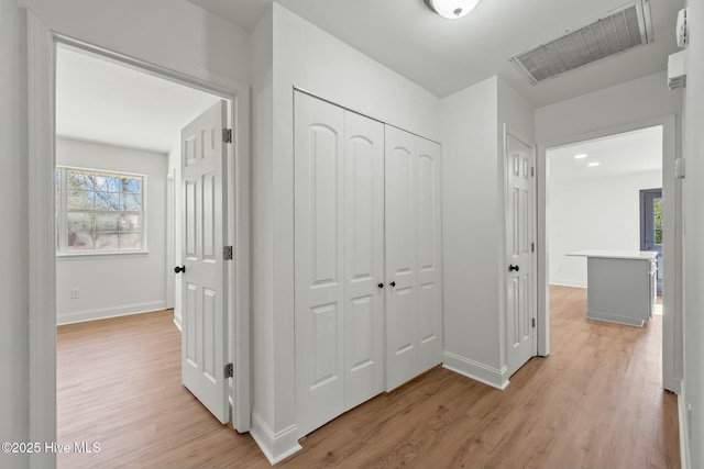 hallway featuring light wood finished floors, visible vents, and baseboards