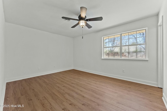 unfurnished room with a ceiling fan, wood finished floors, and baseboards