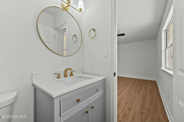 bathroom featuring baseboards, toilet, wood finished floors, and vanity