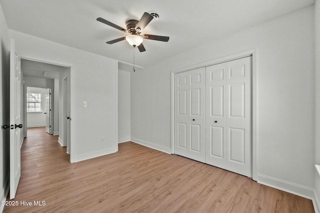 unfurnished bedroom with a closet, baseboards, and light wood-style floors