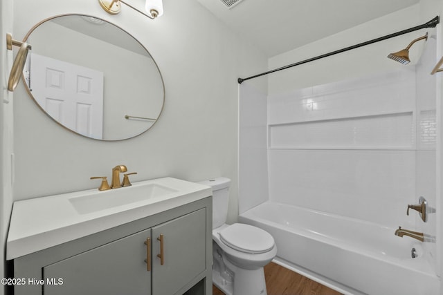 bathroom featuring washtub / shower combination, toilet, vanity, and wood finished floors