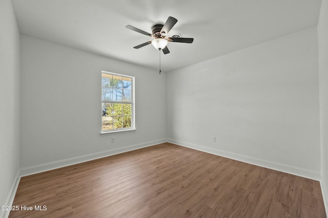 empty room with ceiling fan, baseboards, and wood finished floors