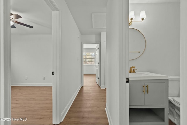 hallway featuring wood finished floors, baseboards, and a sink