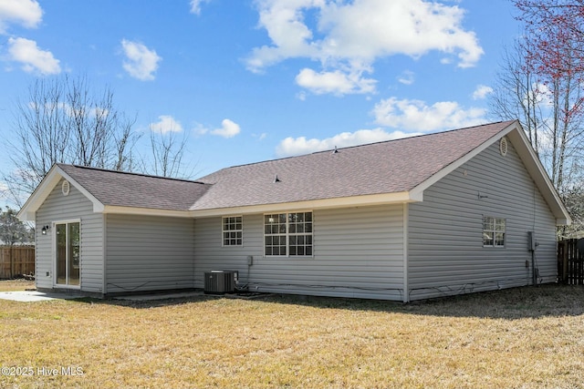 back of property with central air condition unit, a lawn, roof with shingles, and fence