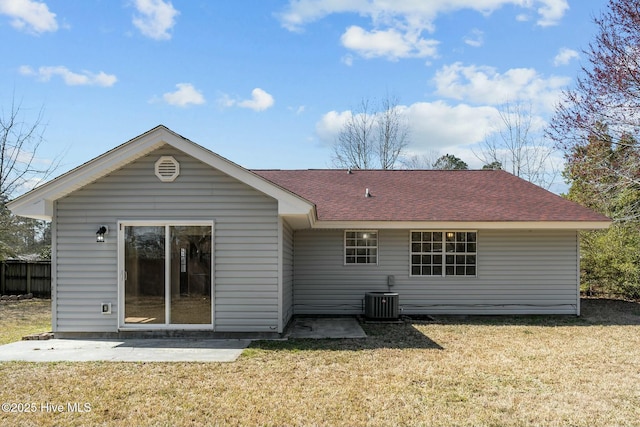 back of house with a yard, roof with shingles, central AC unit, and a patio area