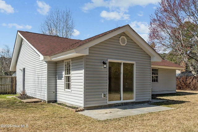 back of house with a lawn, a shingled roof, and fence