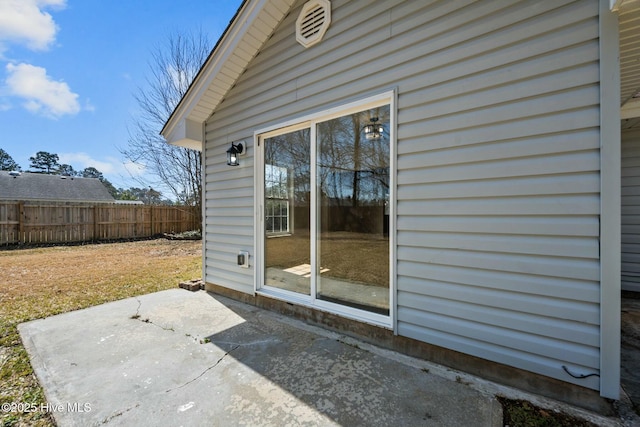 view of exterior entry featuring a patio area and fence