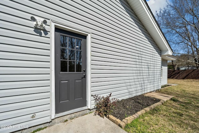 entrance to property with a lawn and fence