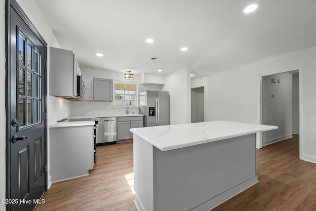 kitchen featuring gray cabinets, stainless steel appliances, light wood-type flooring, and a sink