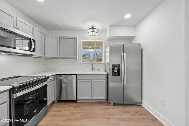 kitchen with light countertops, light wood-style flooring, appliances with stainless steel finishes, and a sink