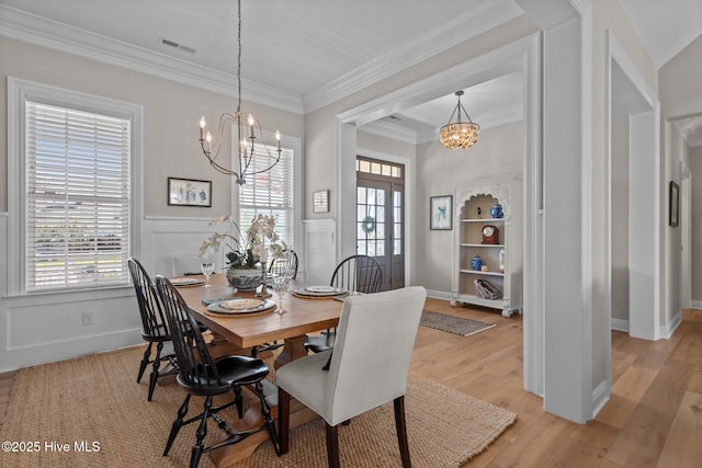 5151 Creswell Dr, Leland, NC 28451 - dining space with a chandelier, light wood-style floors, crown molding, baseboards, and a wainscoted wall