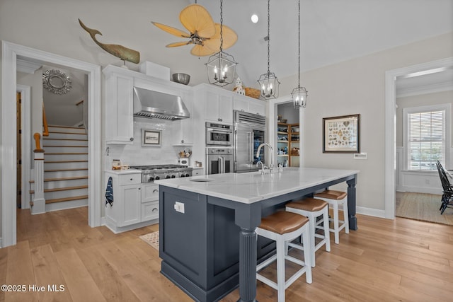 5151 Creswell Dr, Leland, NC 28451 - kitchen with wall chimney exhaust hood, appliances with stainless steel finishes, white cabinetry, light wood-type flooring, and crown molding