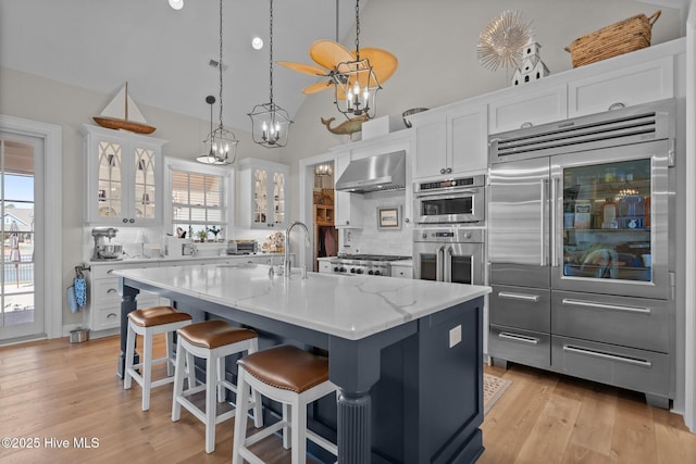 5151 Creswell Dr, Leland, NC 28451 - kitchen with appliances with stainless steel finishes, wall chimney exhaust hood, white cabinets, glass insert cabinets, and a sink